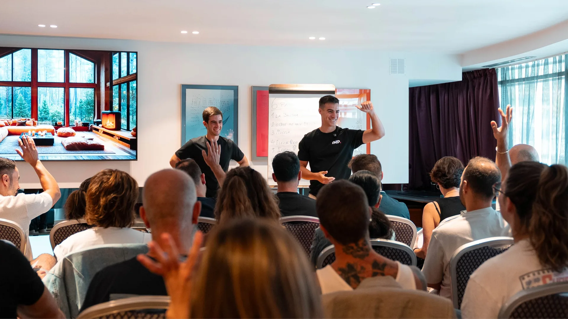 Sergio y Juan durante una sesión del evento presencial de iMP, con la sala llena de asistentes participando